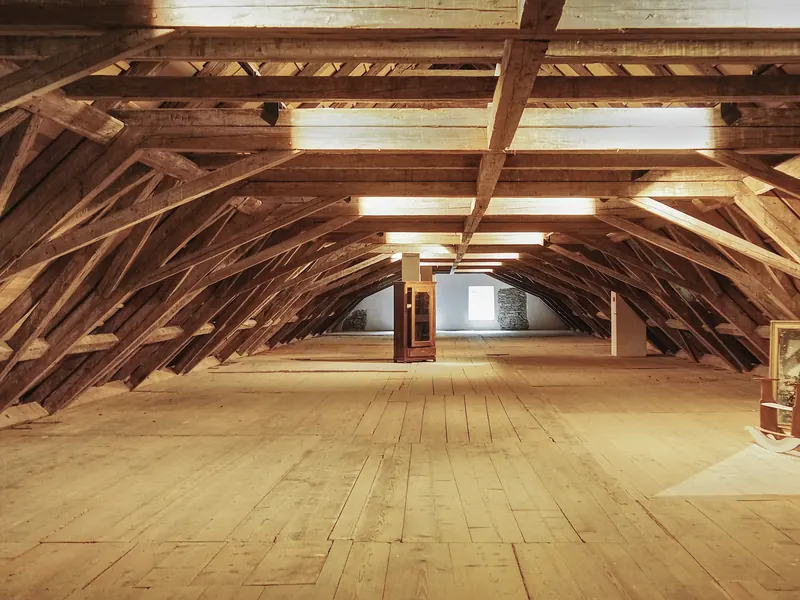 Weiter Dachraum mit tragenden Holzbalken über einem Dielenboden