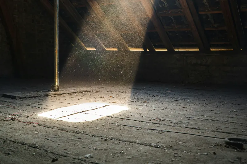 Lichtstrahl fällt durch eine Dachluke auf den Dielenboden eines Dachraums